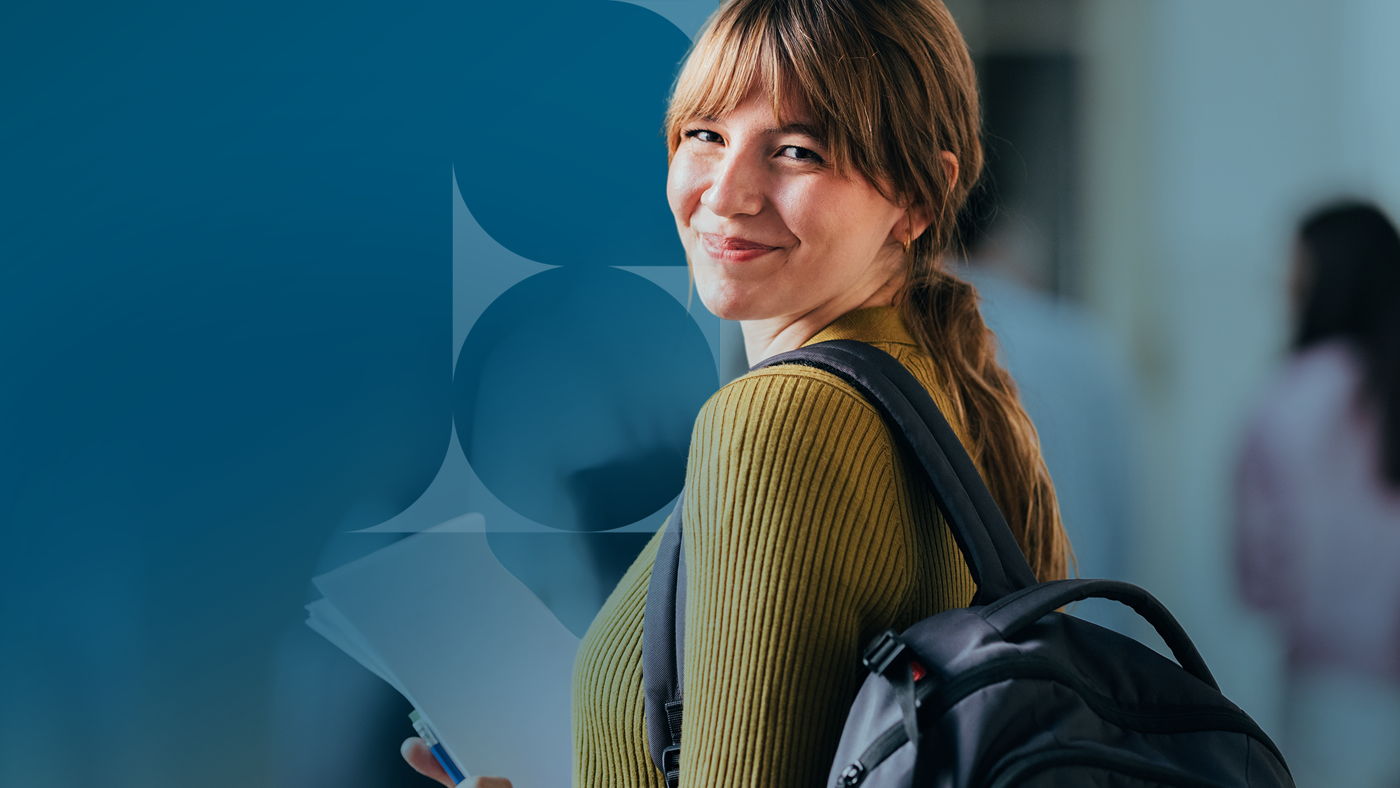 A young woman with a backpack looks over her shoulder and smiles at the camera, holding papers. The background is a modern building with an abstract blue design.