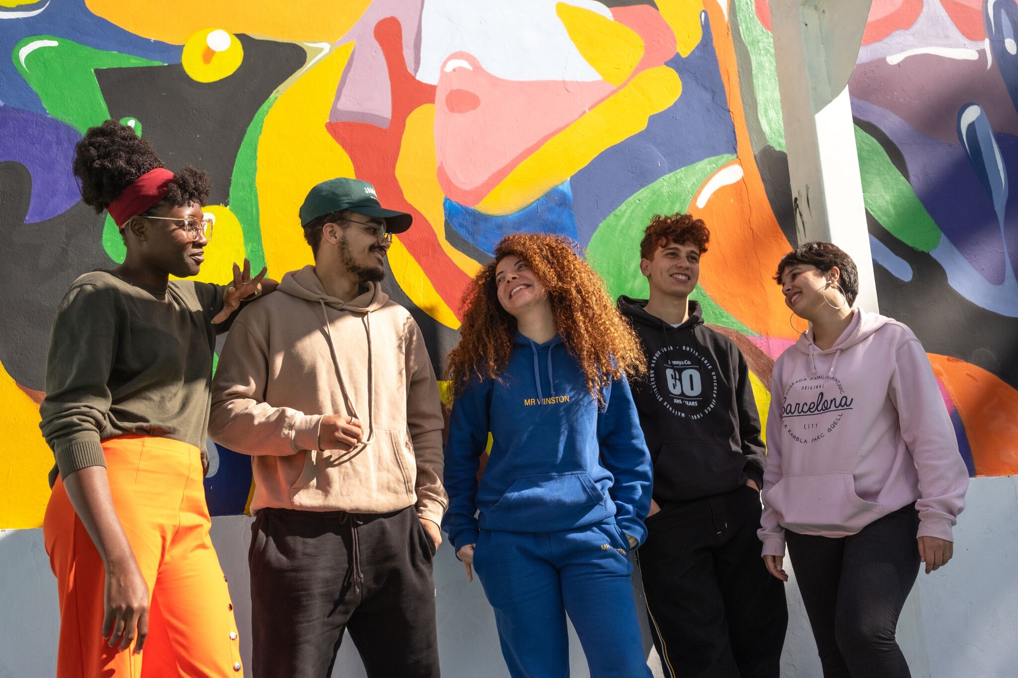 A diverse group of friends sharing a laugh in front of a vibrant street art mural.