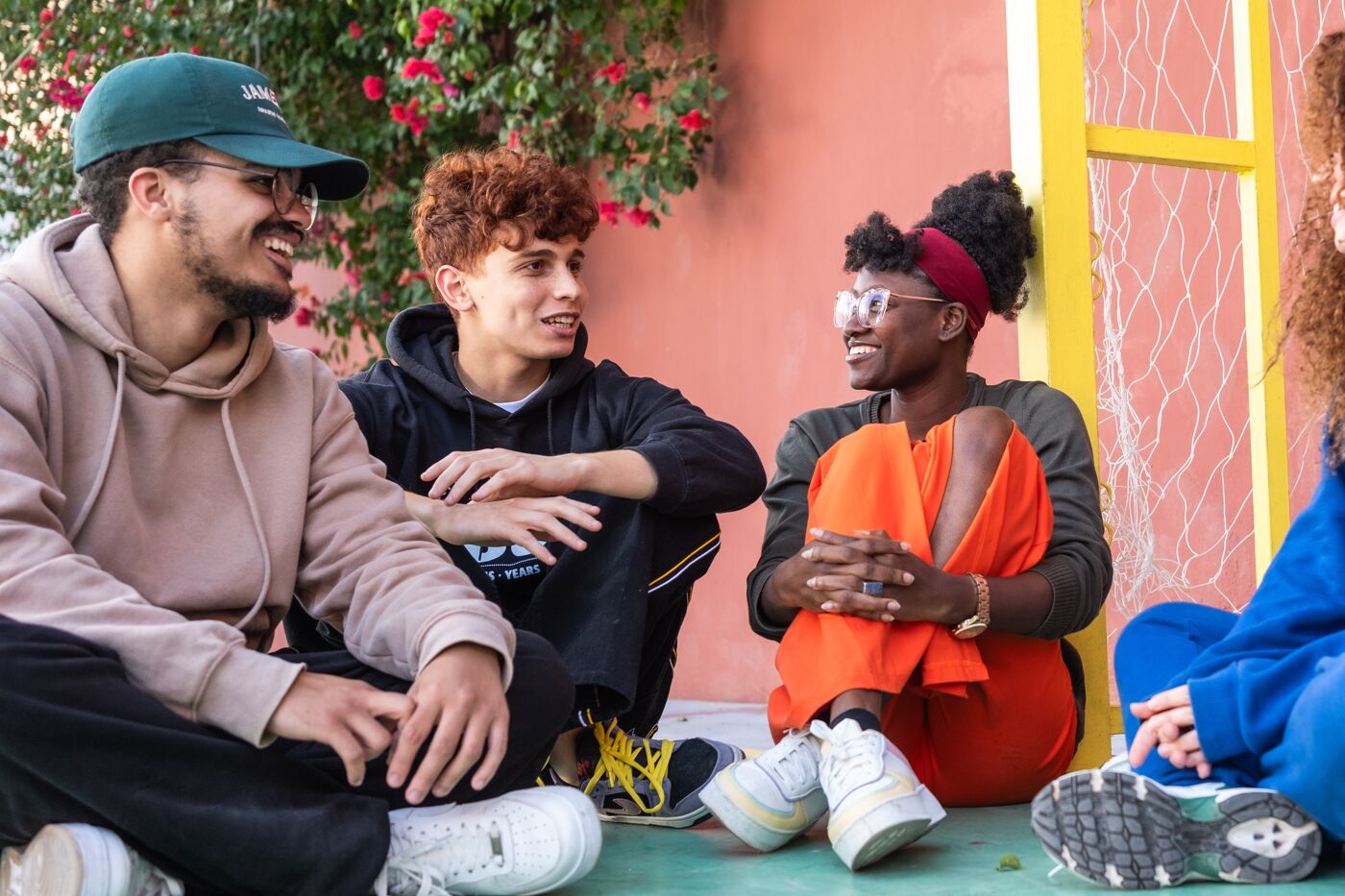 A group of young adults engaged in a cheerful conversation on a bench, surrounded by a quaint setting.