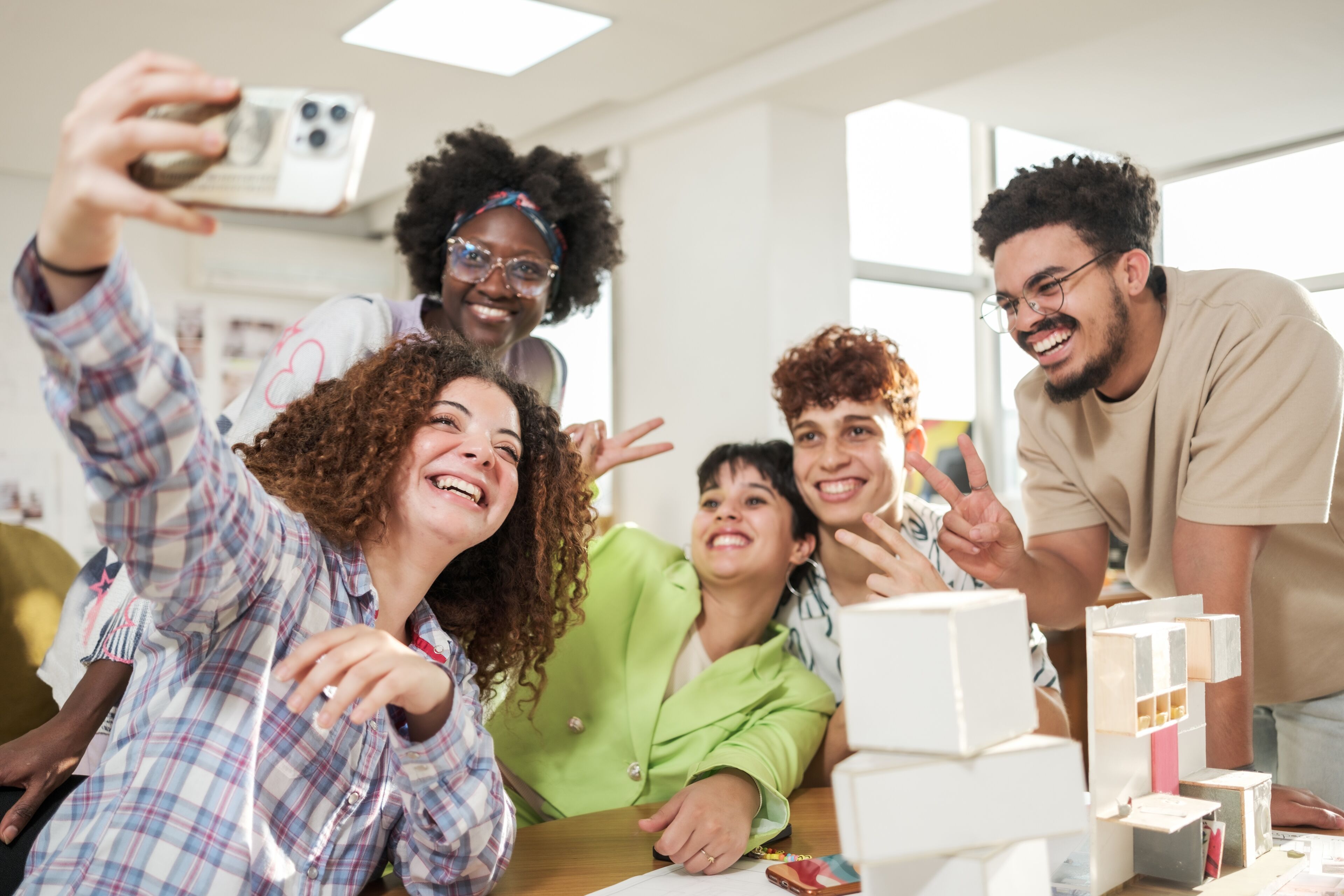 A joyful team takes a group selfie in a creative workspace.