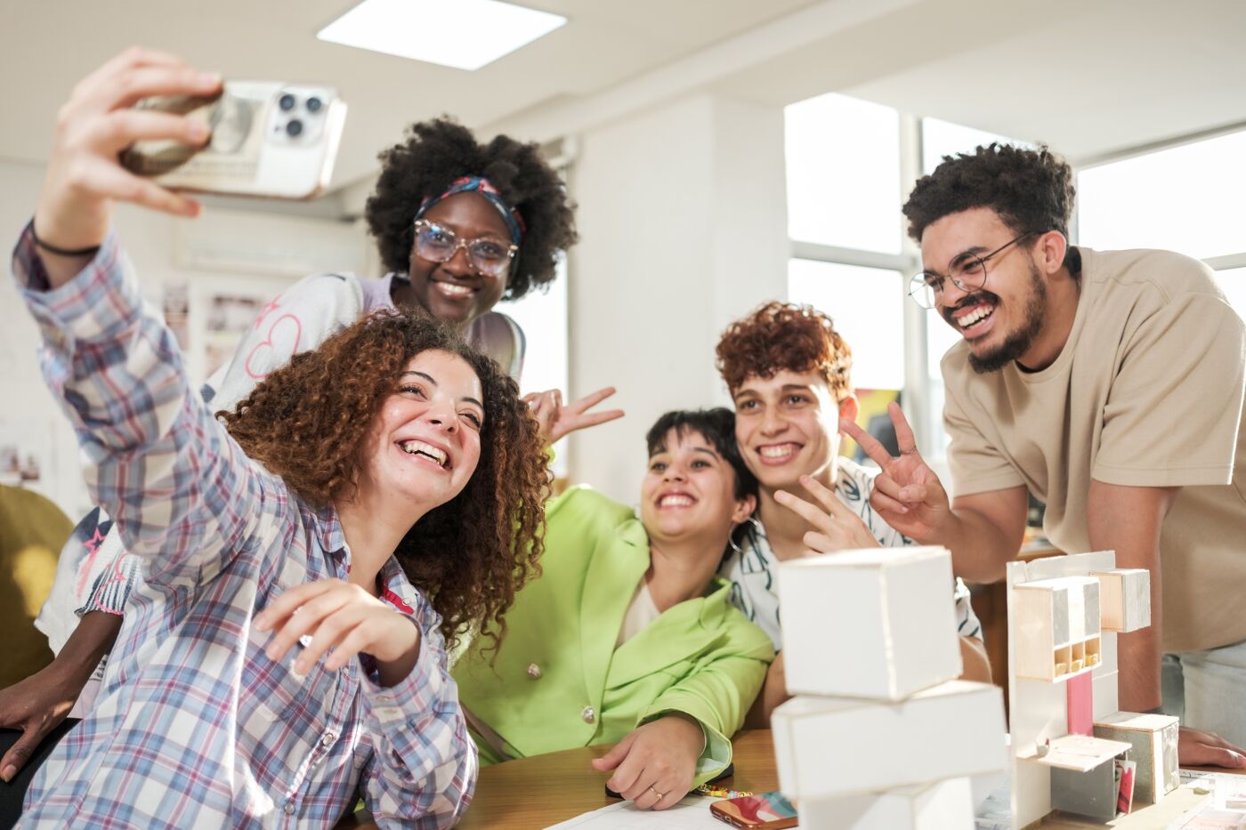 A joyful team takes a group selfie in a creative workspace.