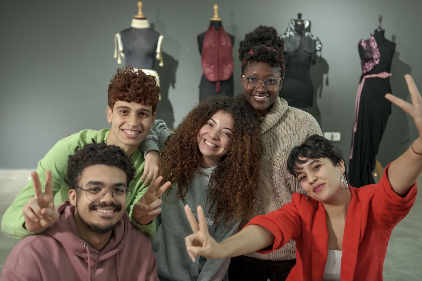 Fashion design students sharing a joyful moment in a group selfie, with creative projects in the background.