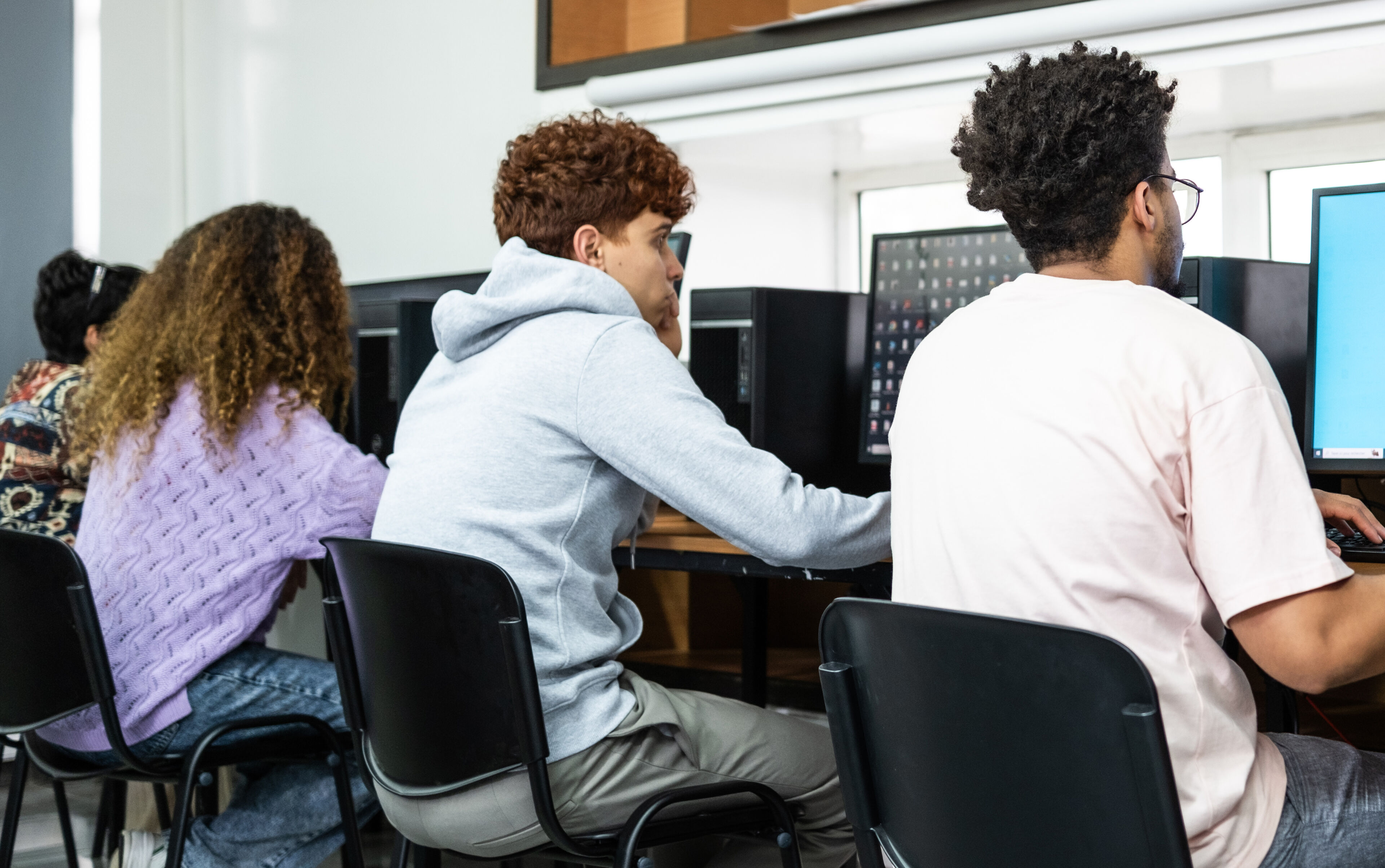 Groupe d'étudiants concentrés sur leurs tâches dans un laboratoire informatique.