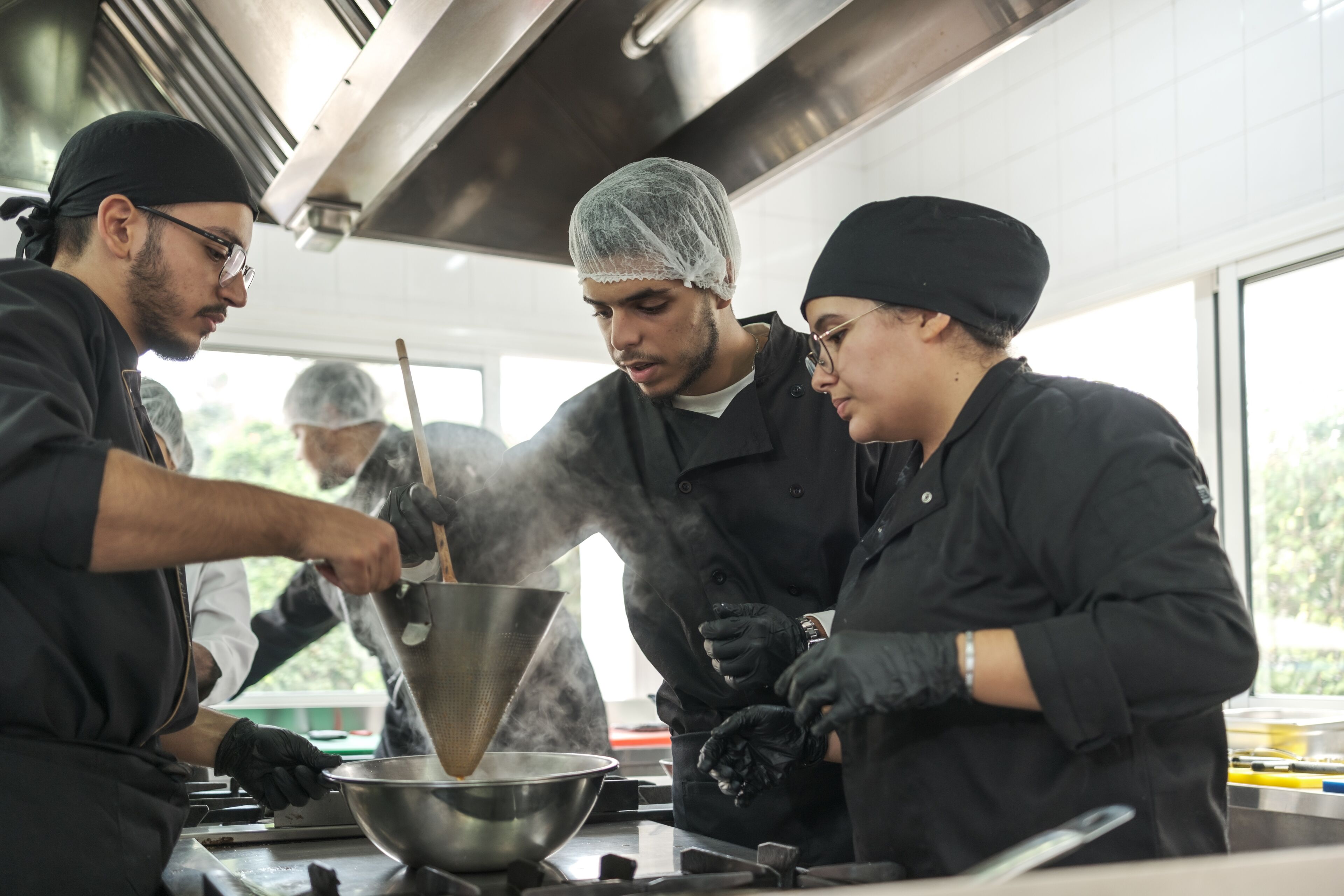 Une équipe de chefs dans une cuisine animée prépare un plat en collaboration avec concentration et expertise.