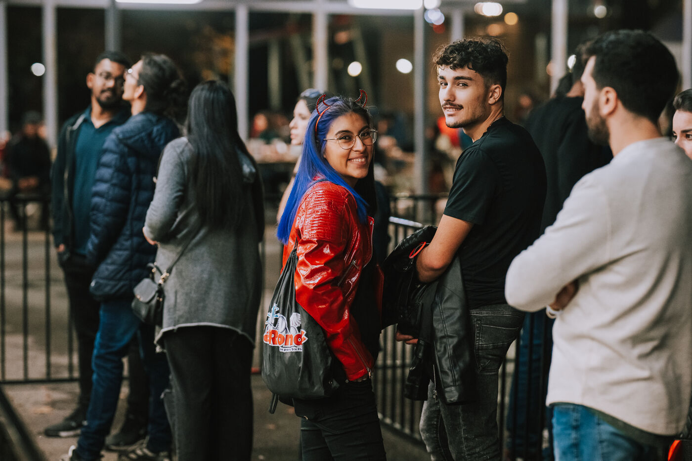 Two friends sharing a laugh while waiting in line, surrounded by the lively atmosphere of the evening.