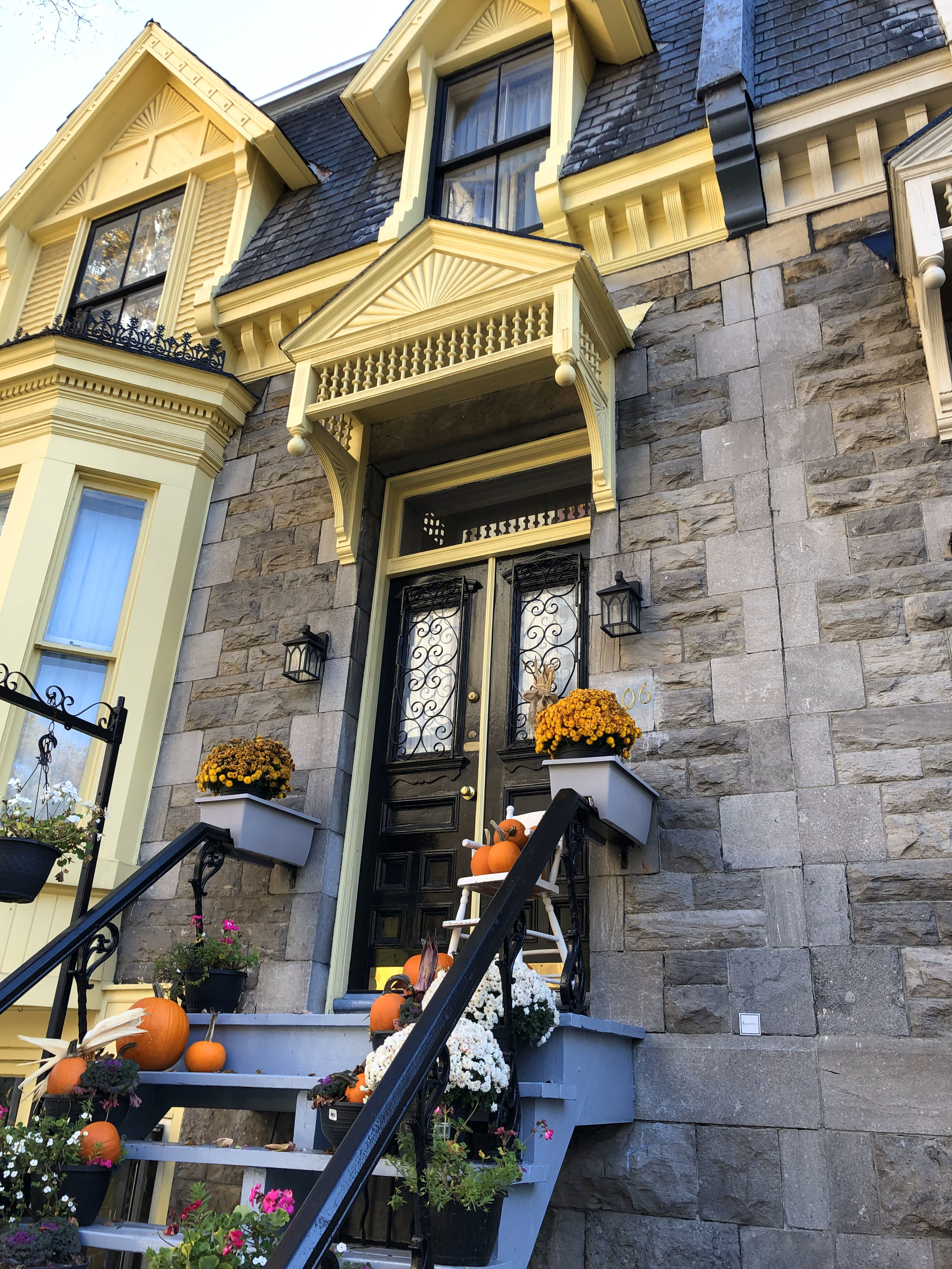 A charming stone house entrance adorned with fall decorations and pumpkins, welcoming the season.