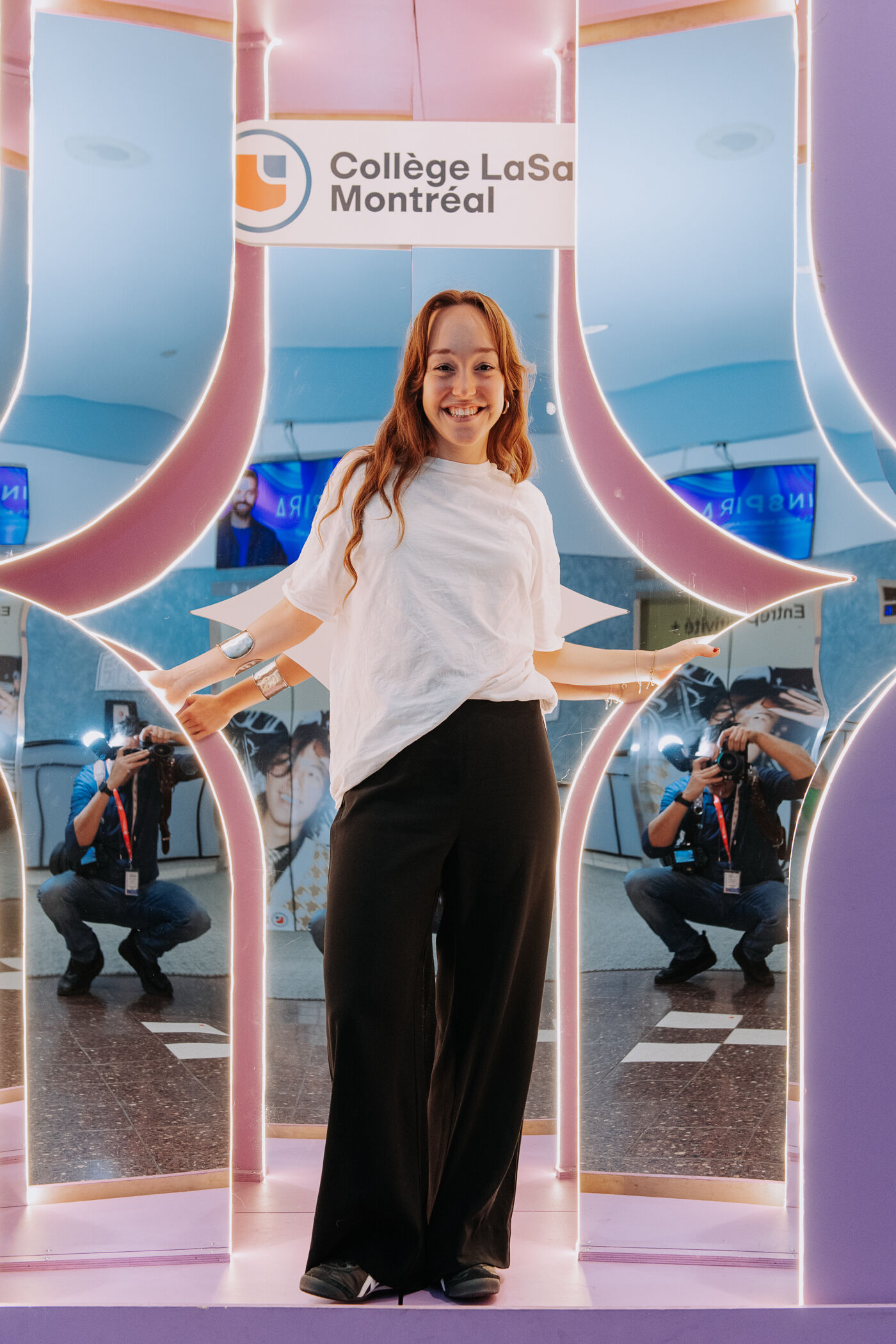 The image features a woman standing in front of a mirror, smiling and posing for a picture.