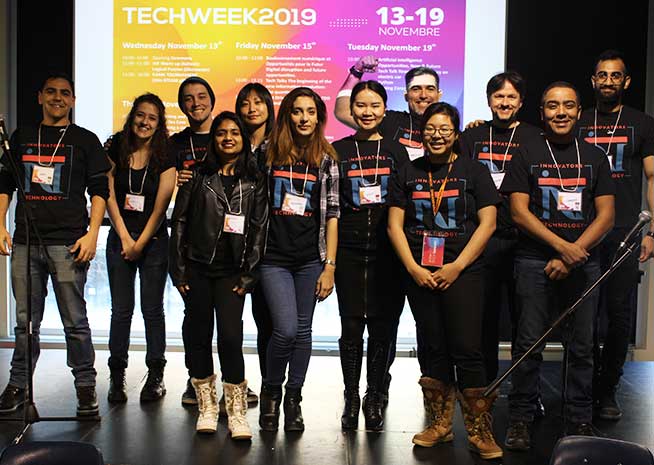 Un groupe hétérogène de personnes en t-shirts assortis, souriant lors d'un événement Tech Week.