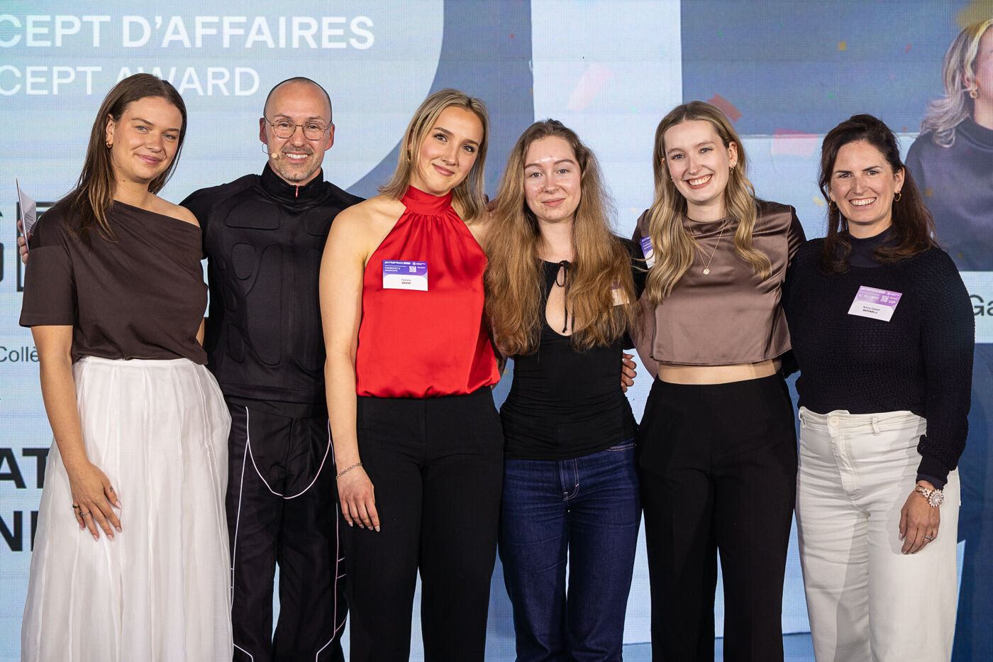Six women and one man pose for a photo at an event. They all appear to be smiling and posing for the camera.