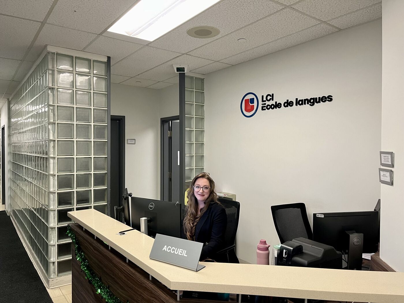 A welcoming reception area of LCI Language School with a staff member ready to assist and signage overhead.