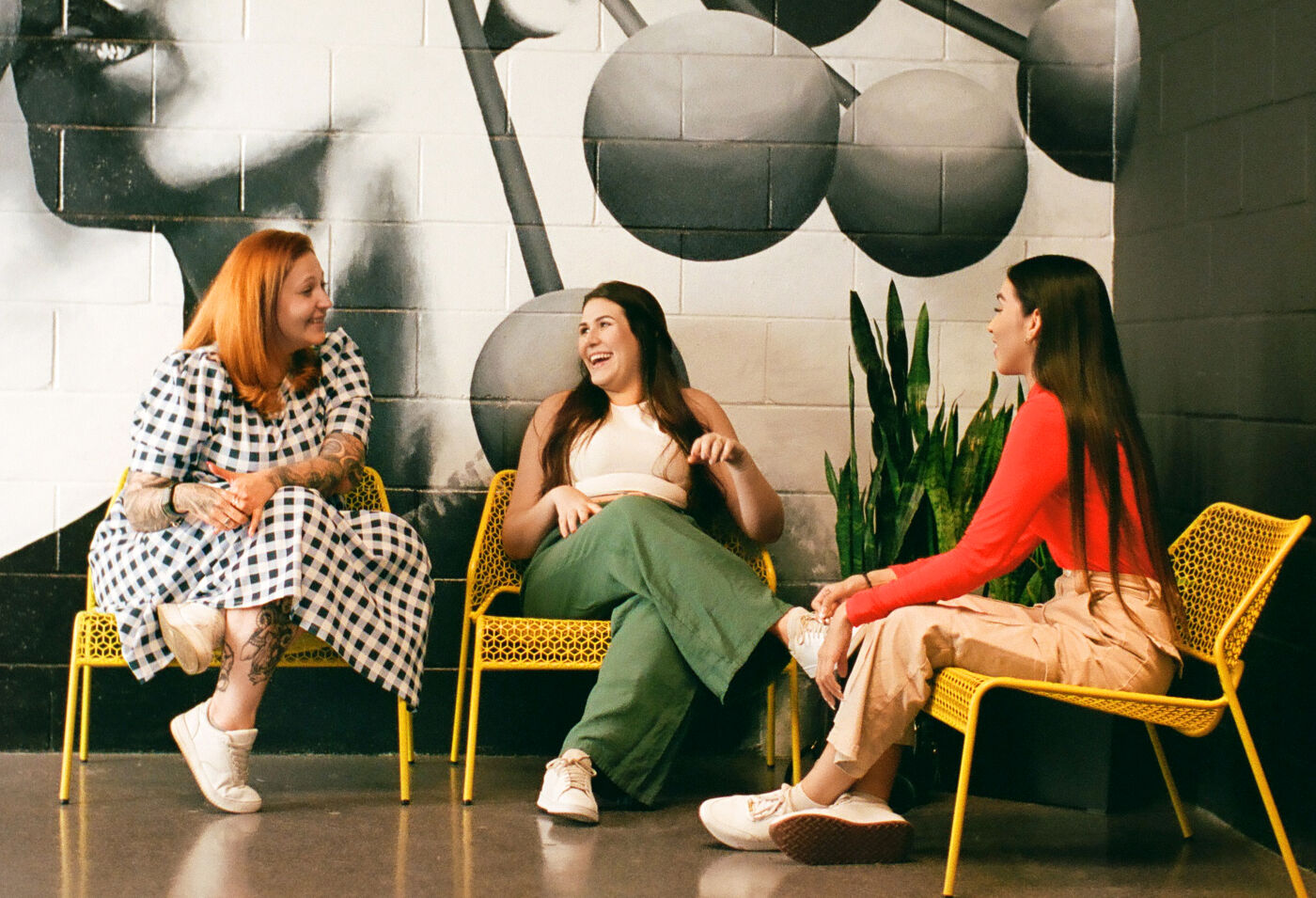 Three individuals in casual attire engage in a relaxed conversation in a creatively adorned space.