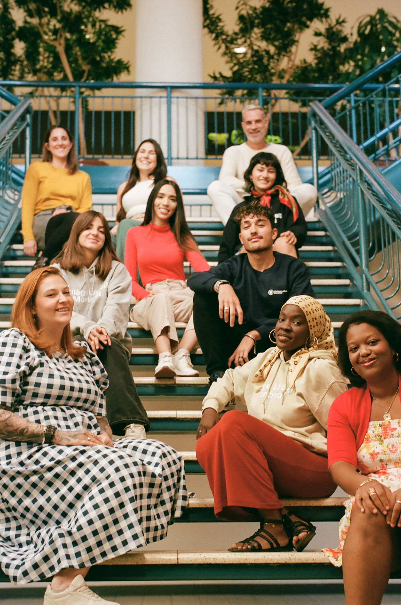 A group of students of diverse backgrounds sits together on stairs, symbolizing unity and ambition.