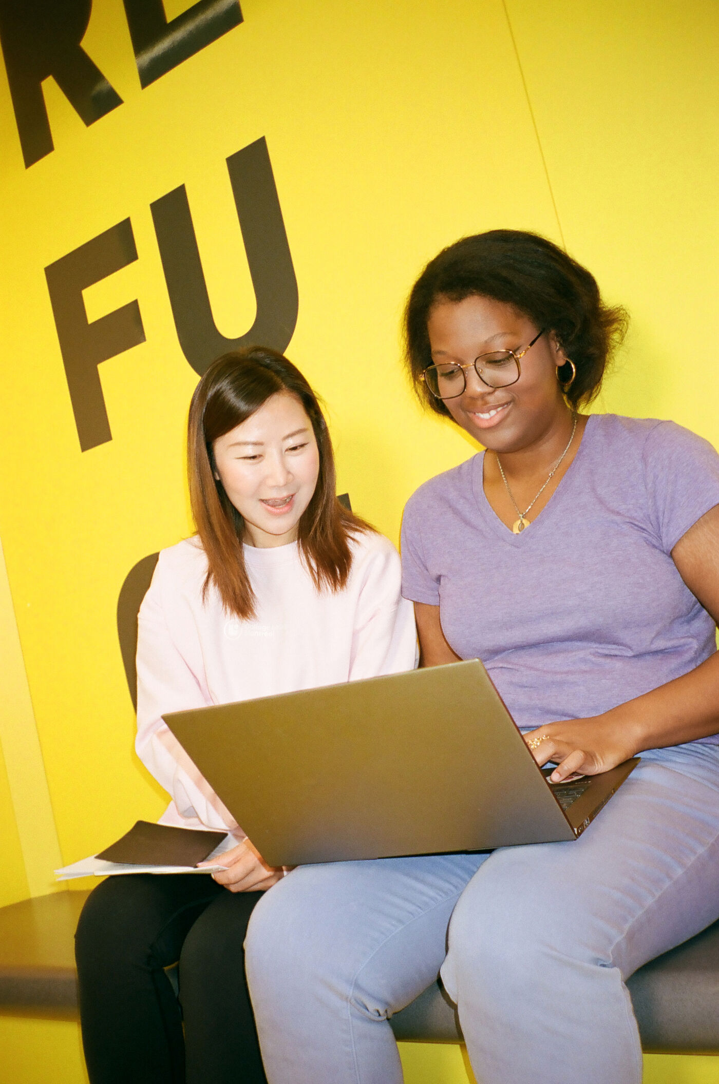 Two professionals work together, focusing on a project with smiles.
