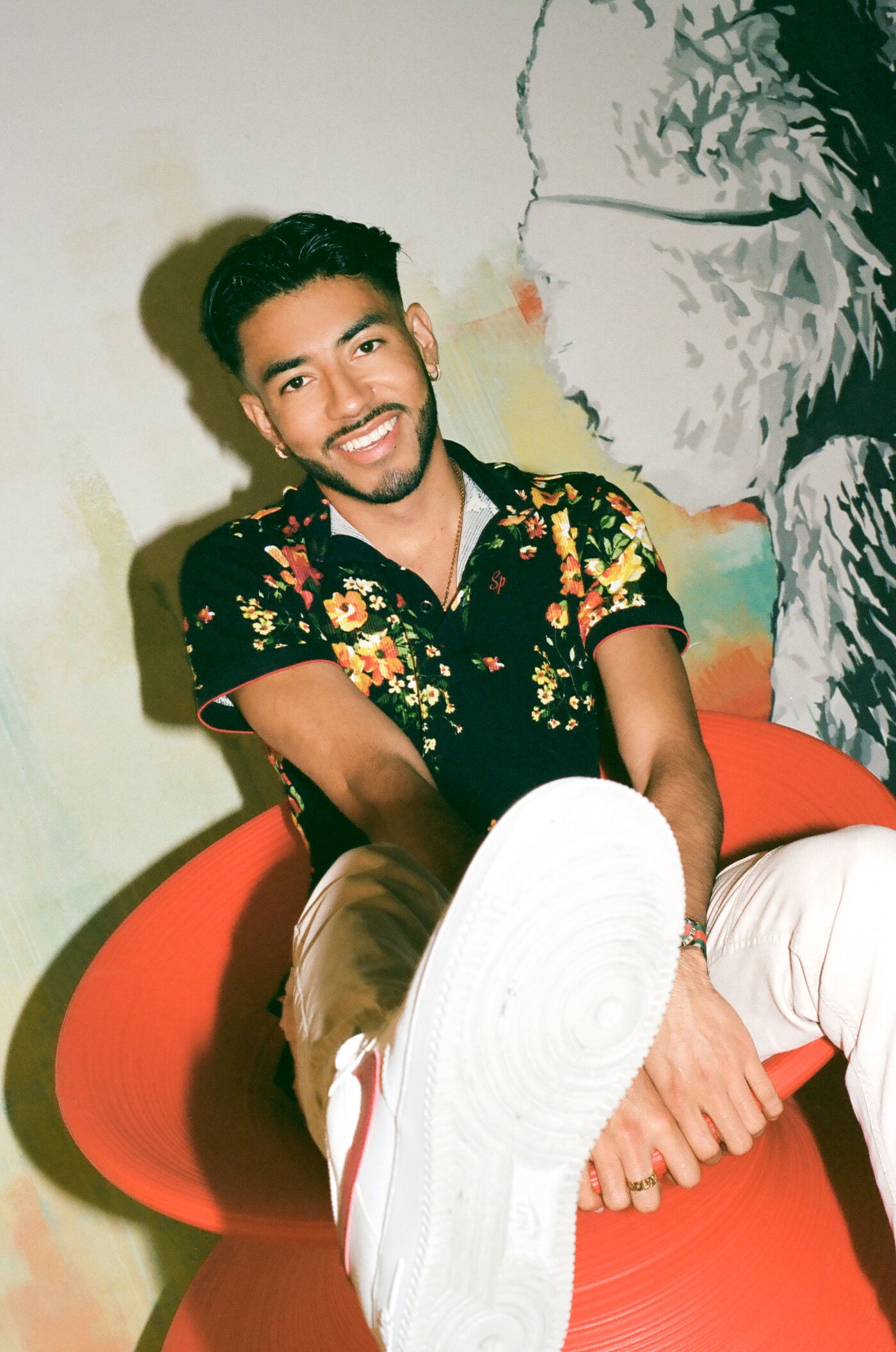 Man in a floral shirt exudes confidence on a striking red seat.