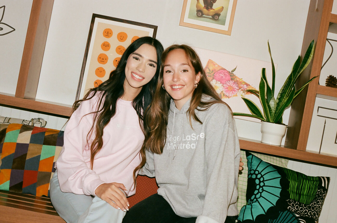 Two smiling friends posing for a cozy picture at home.