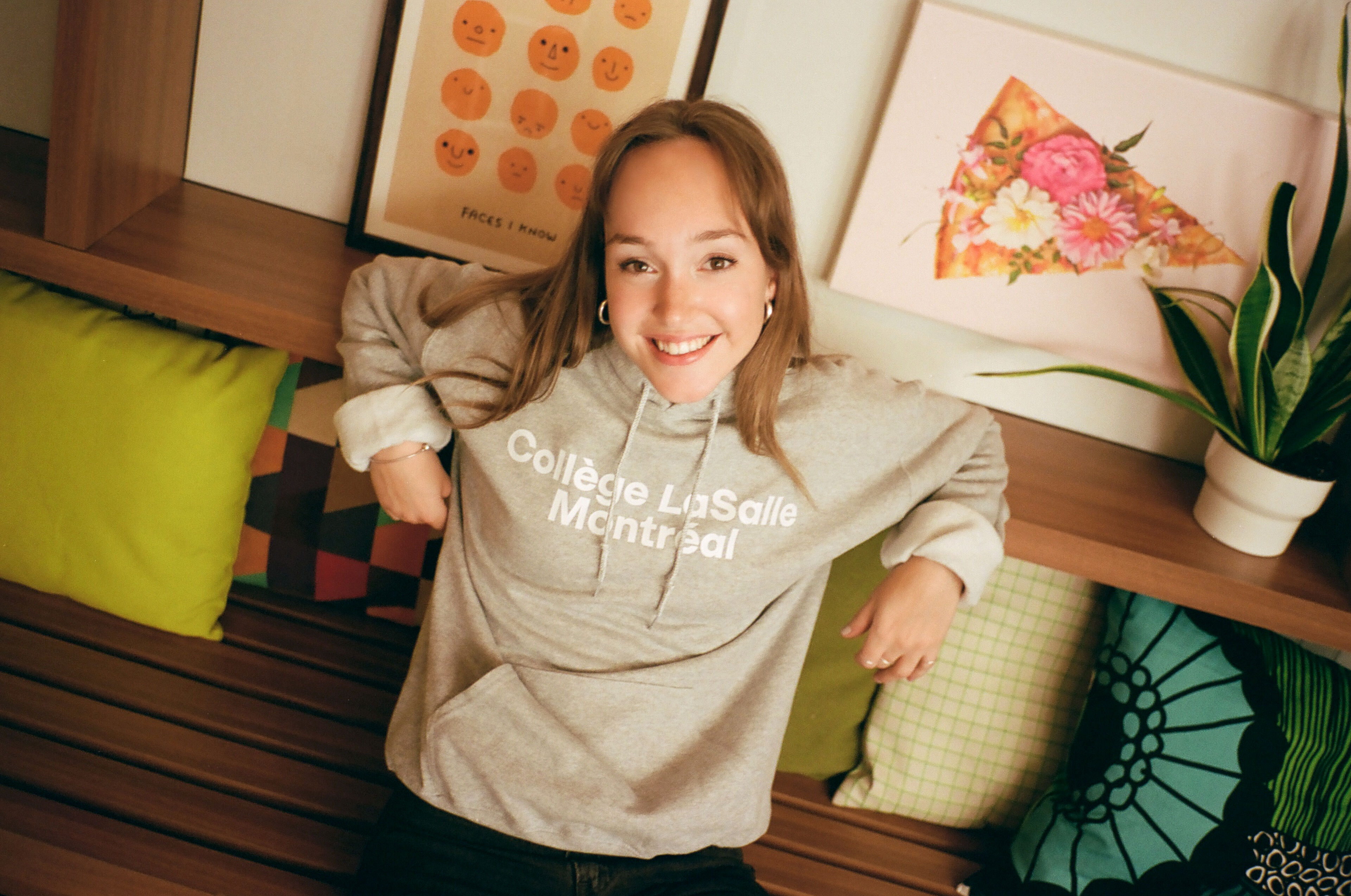 A cheerful student showcases her college pride in a cozy branded sweatshirt.
