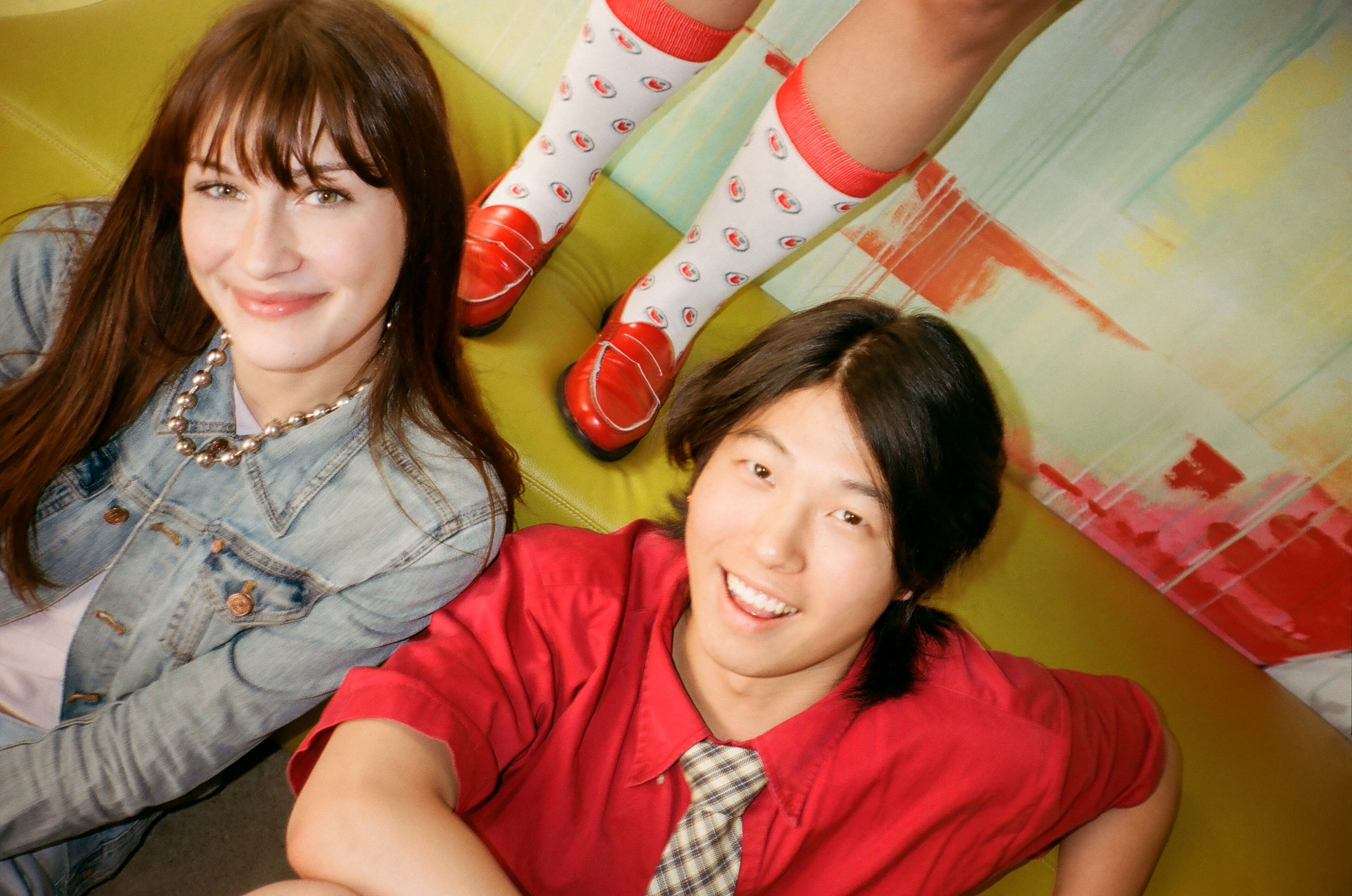 Two friends lounge against a vibrant backdrop, their smiles as bright as their surroundings.