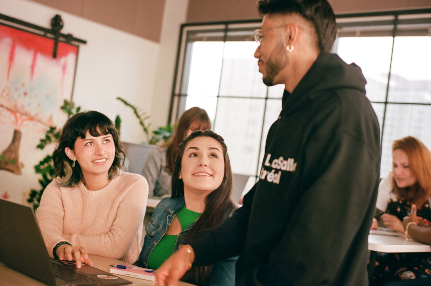 A cheerful discussion among college students and their mentor in a bright classroom.