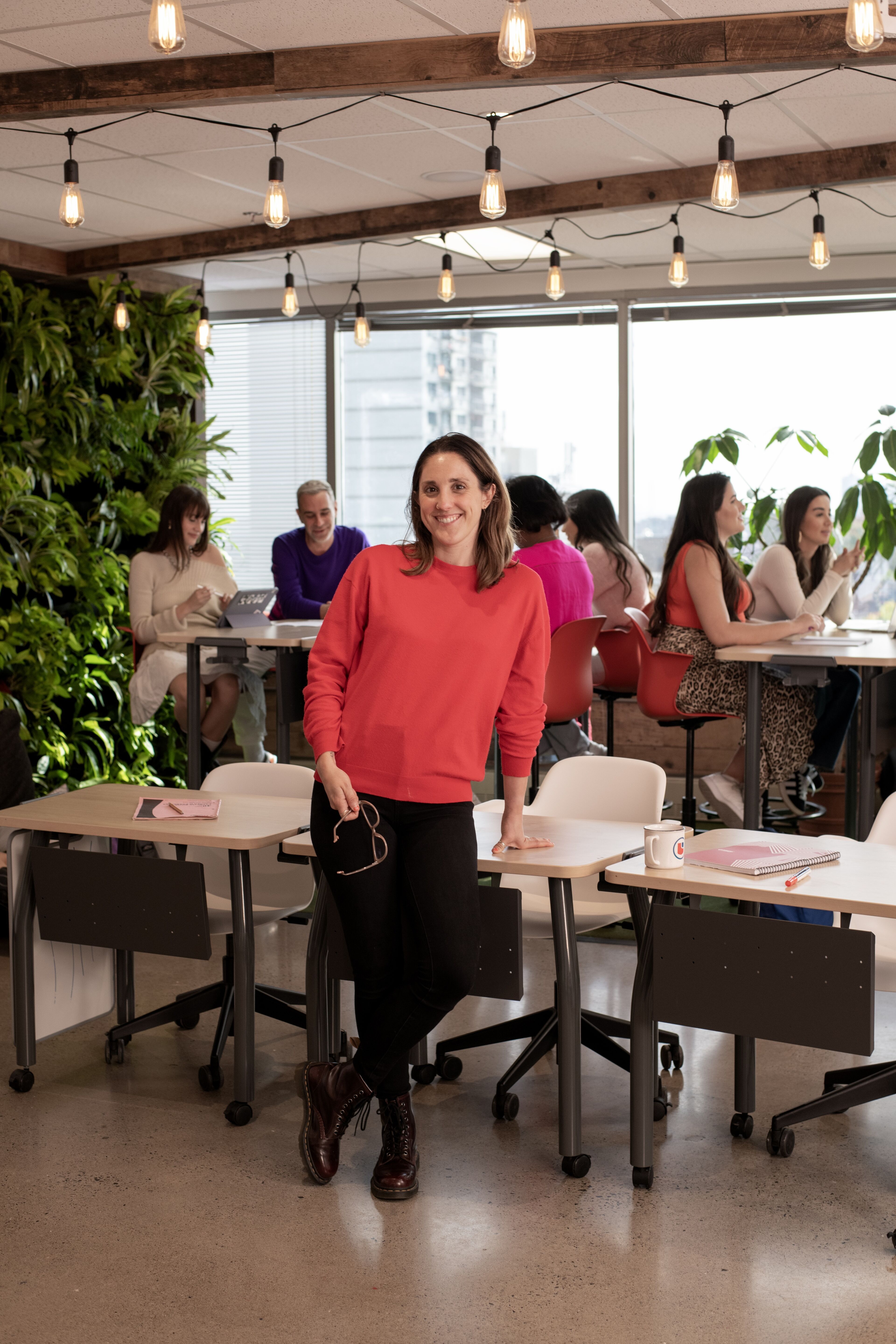 A smiling instructor stands confidently in a vibrant classroom setting, ready to begin the lesson.