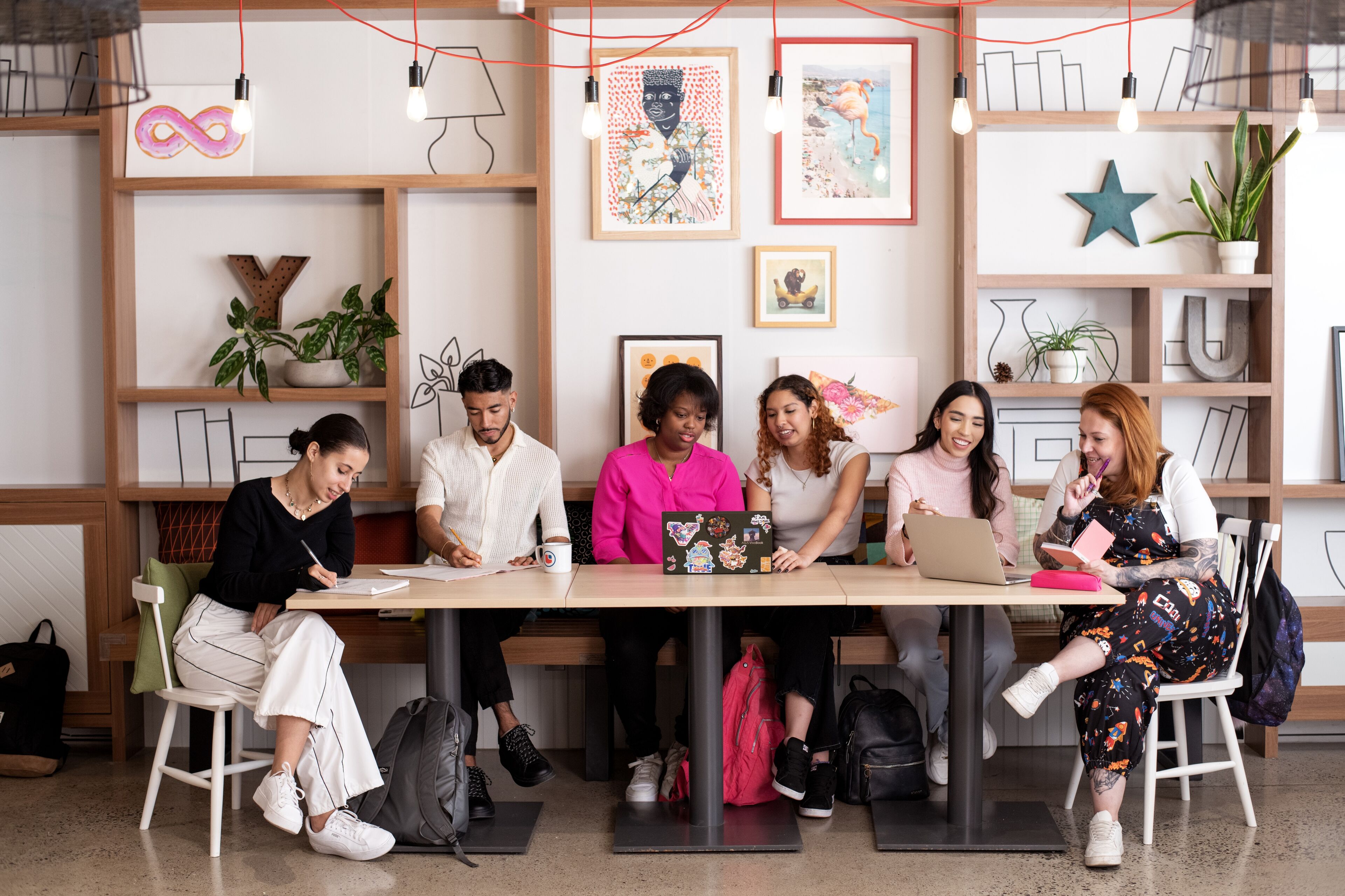 A diverse group of focused individuals engaged in creative work at a modern shared workspace.