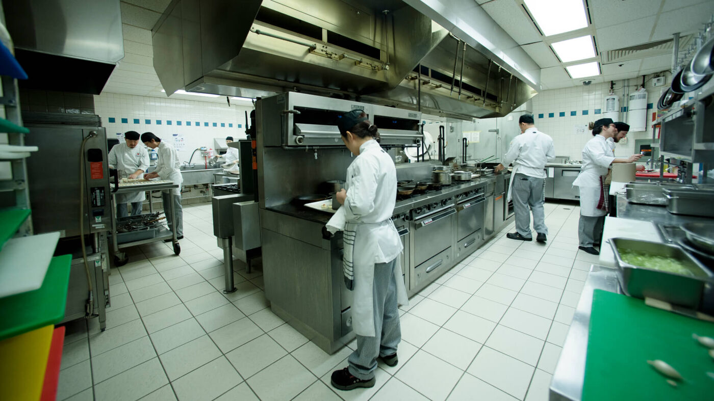 Chefs in a bustling commercial kitchen preparing dishes with precision and care.