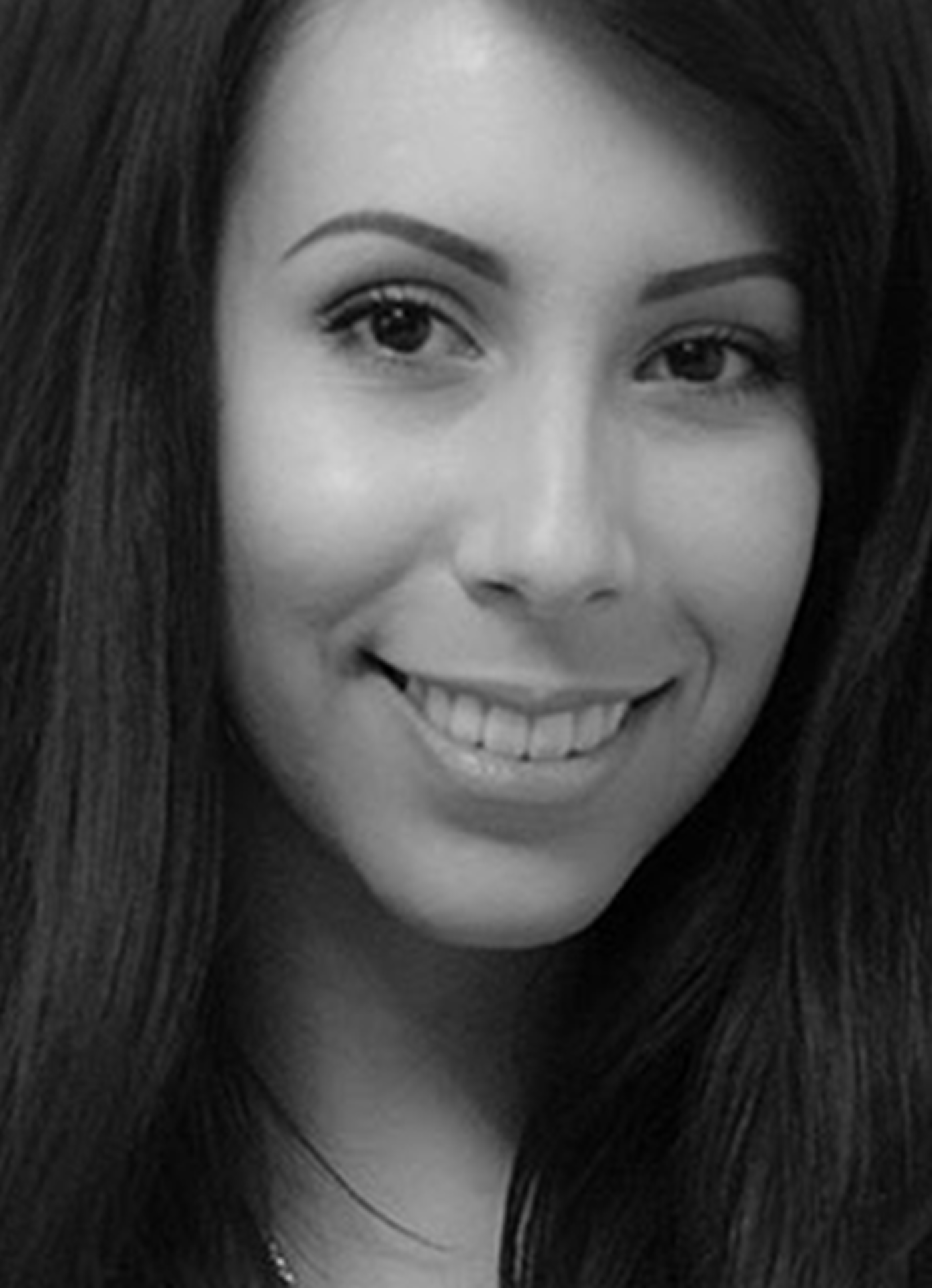 Close-up of a smiling woman with long hair in a black and white photograph.