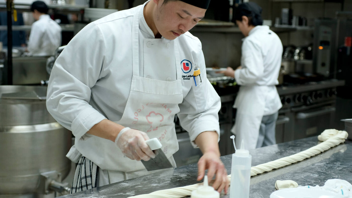 A culinary student from LaSalle College meticulously preparing dough in a professional kitchen environment.