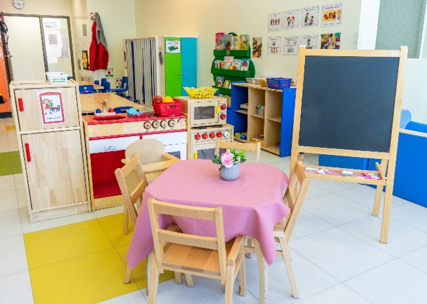 A vibrant preschool room with colorful educational toys, child-sized furniture, and a blackboard, encouraging playful learning.