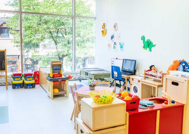 Une salle de classe de maternelle bien éclairée avec divers postes d'apprentissage et jouets, prête pour une journée d'activités.