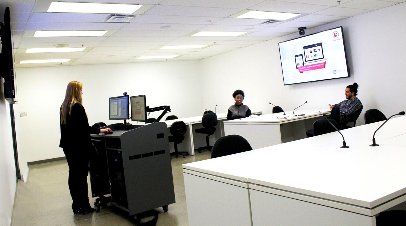 An employee conducting a presentation in a corporate training room, with participants seated at the conference table.