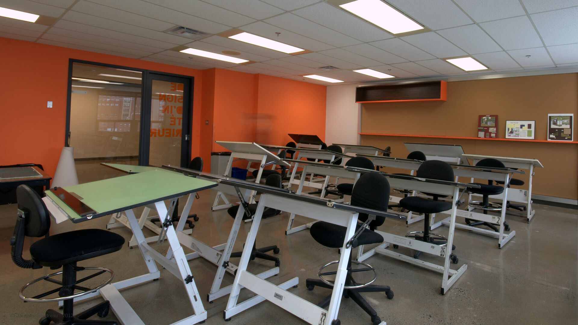 Une salle de dessin technique éducative avec planches à dessin et tabourets, vide et prête pour un cours d'art.