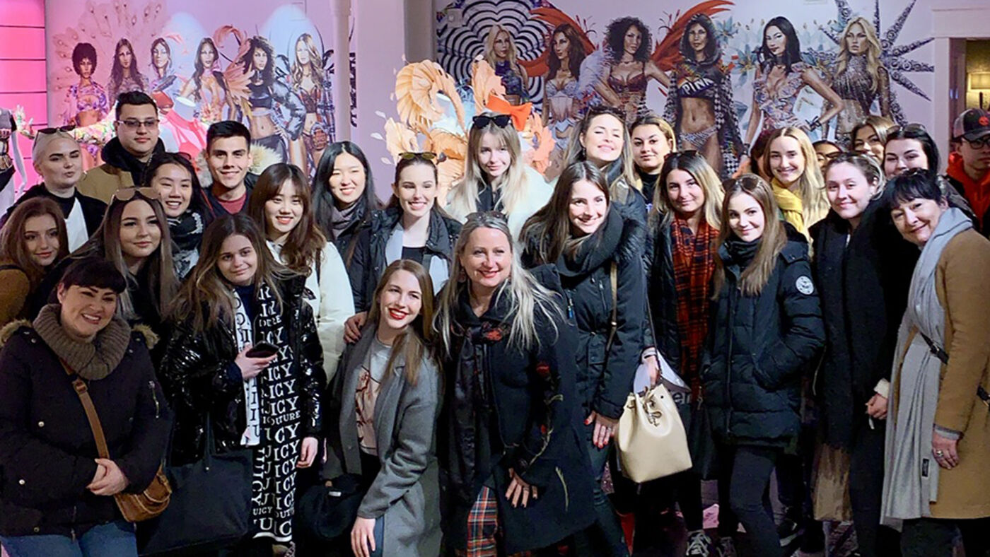 A diverse group of individuals posing for a photo, smiling, and dressed in winter attire, possibly at a social gathering.