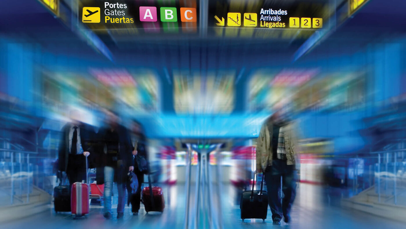 Travelers with luggage in a bustling airport terminal, with colorful signage and a motion blur effect conveying movement and haste.