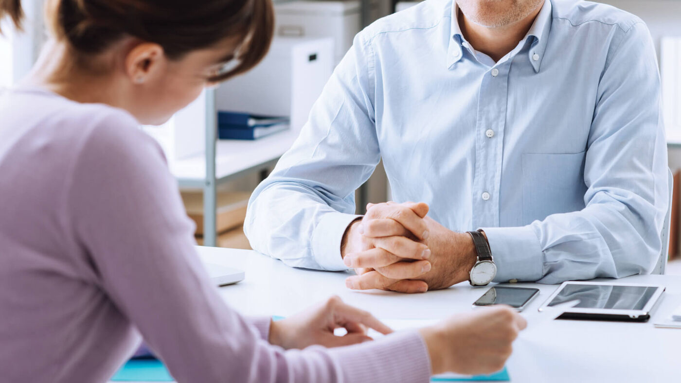 A man in a blue shirt attentively listens during a meeting with a female colleague.