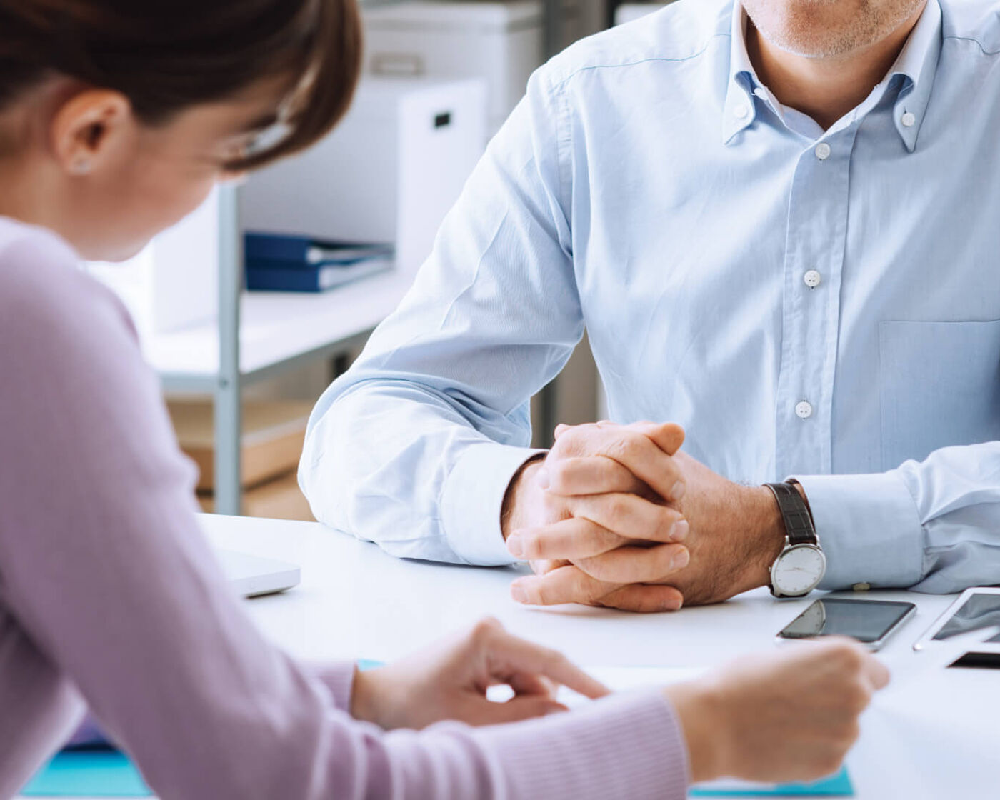 A man in a blue shirt attentively listens during a meeting with a female colleague.