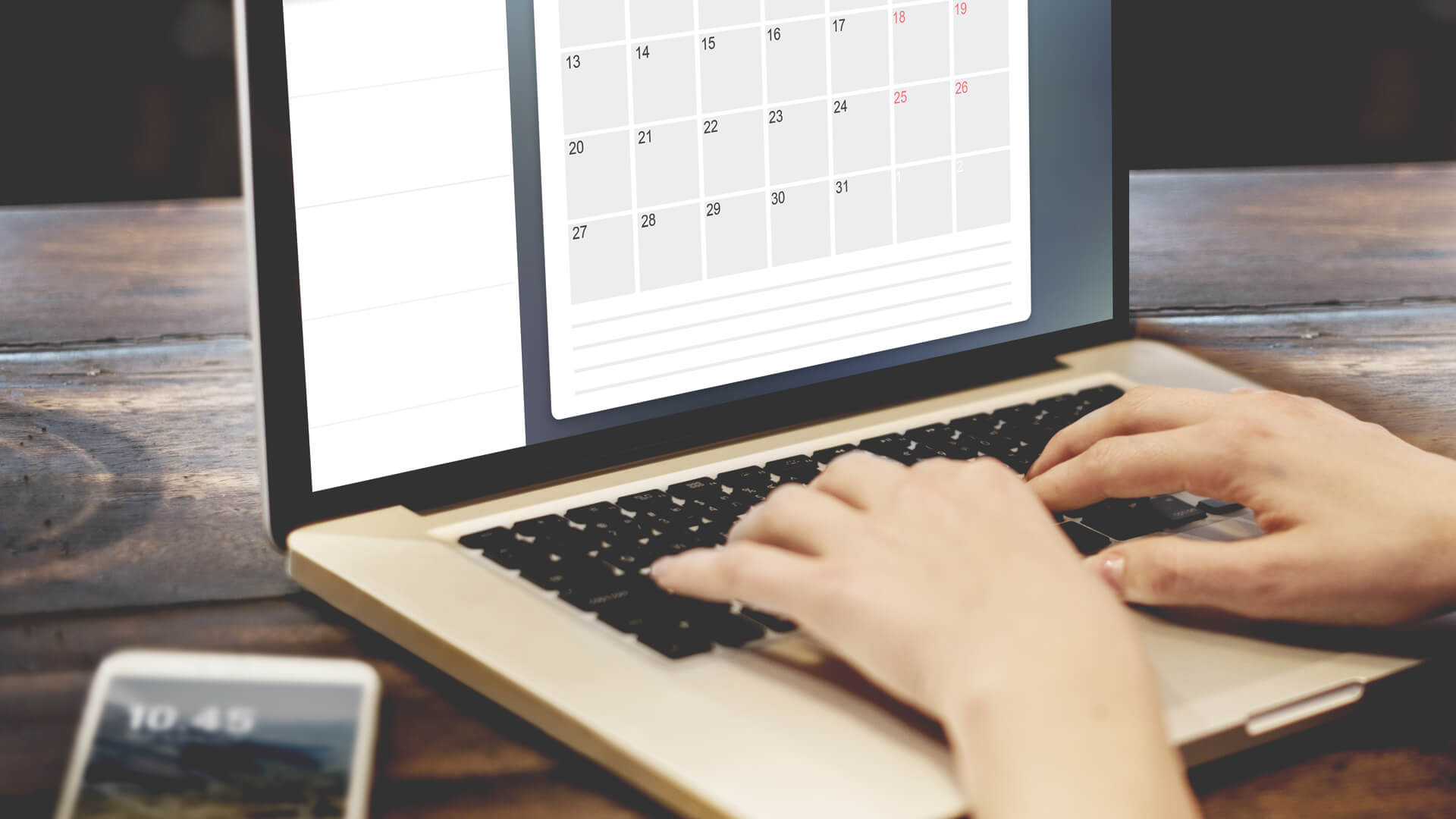 A person scheduling tasks on a digital calendar on their laptop, alongside a smartphone displaying the time.