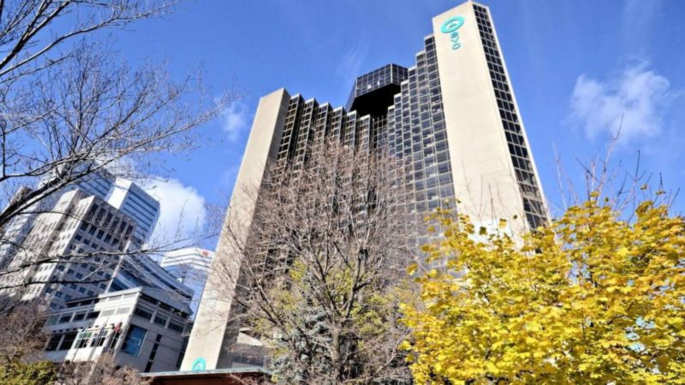 The façade of a tall skyscraper adorned with the 'evo' logo, set against a clear sky amidst an urban backdrop with autumn foliage.