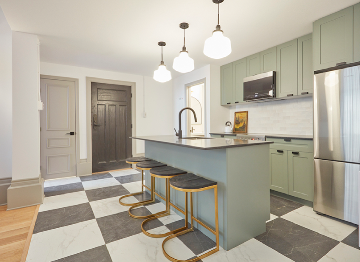 The image shows a kitchen with a large island, a sink, and a dining table. The kitchen is clean and well-lit, with a modern design.