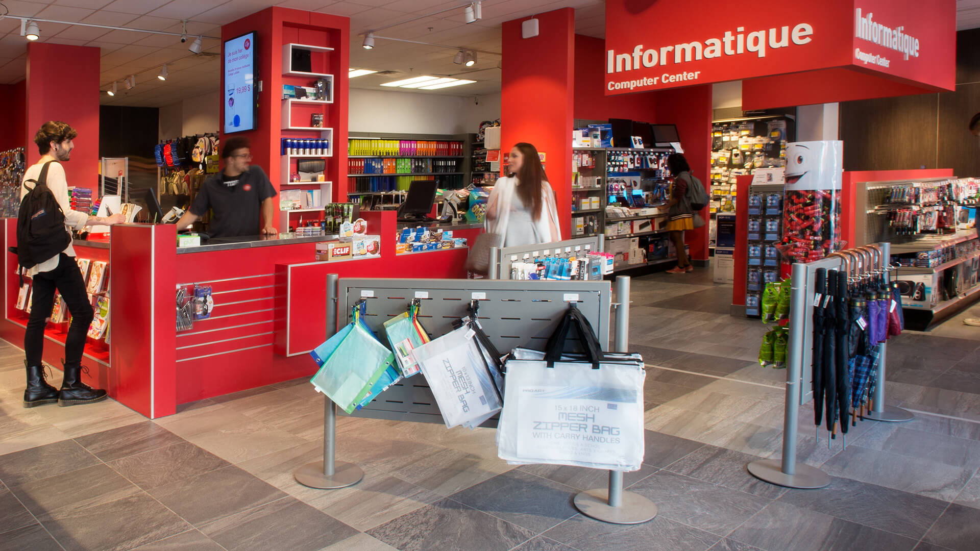 Des clients examinent les produits dans un magasin d'électronique bien agencé avec un décor rouge vif.
