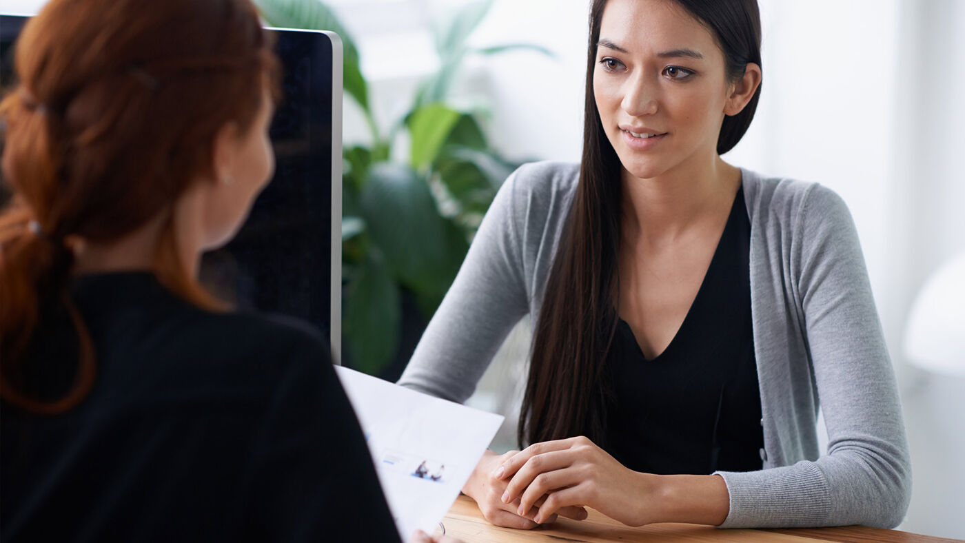 A potential employee engages in a job interview with a female interviewer in a professional office setting.