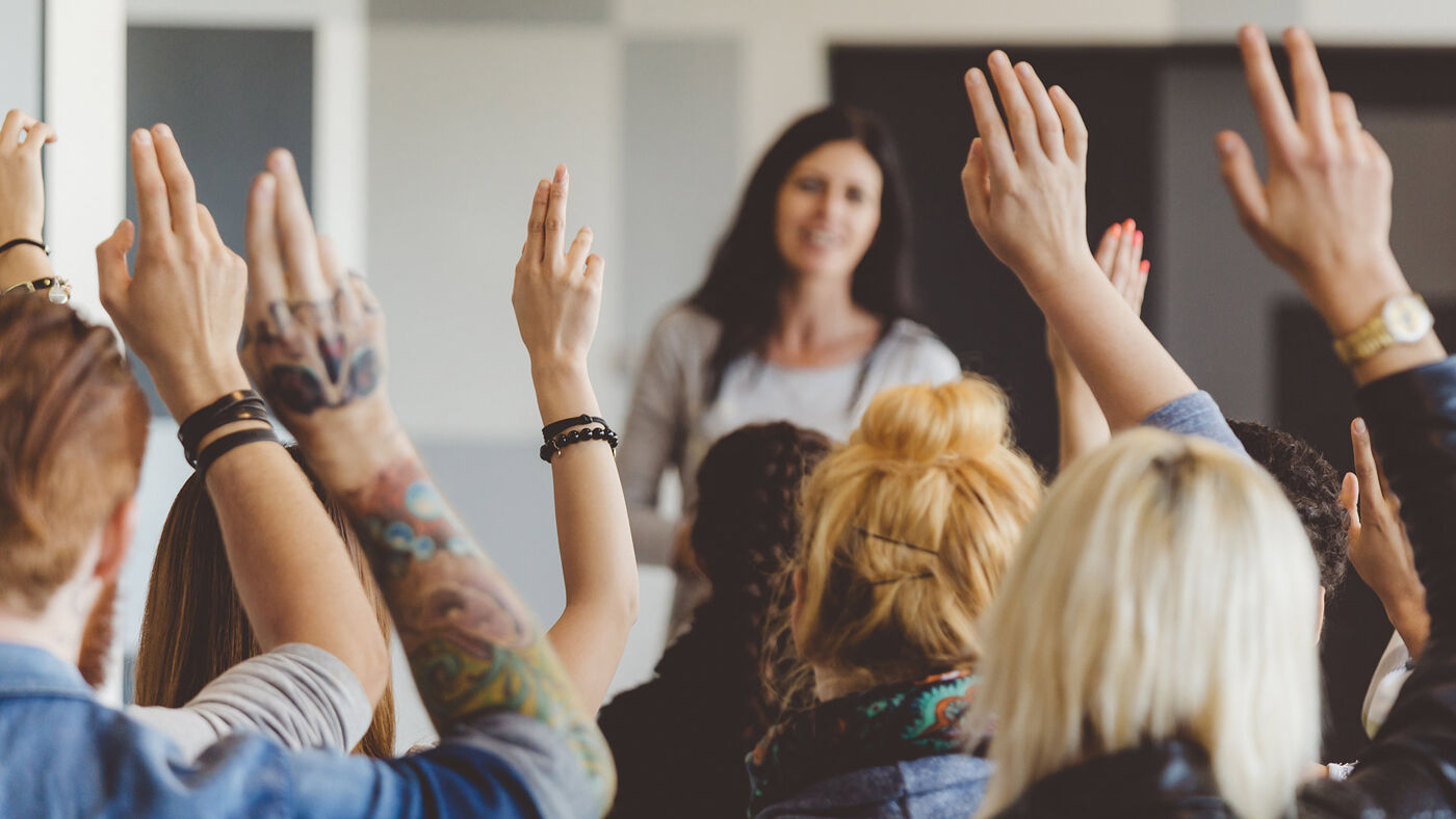 Audience clapping for a speaker at a workshop, viewed from the back in a well-lit room.