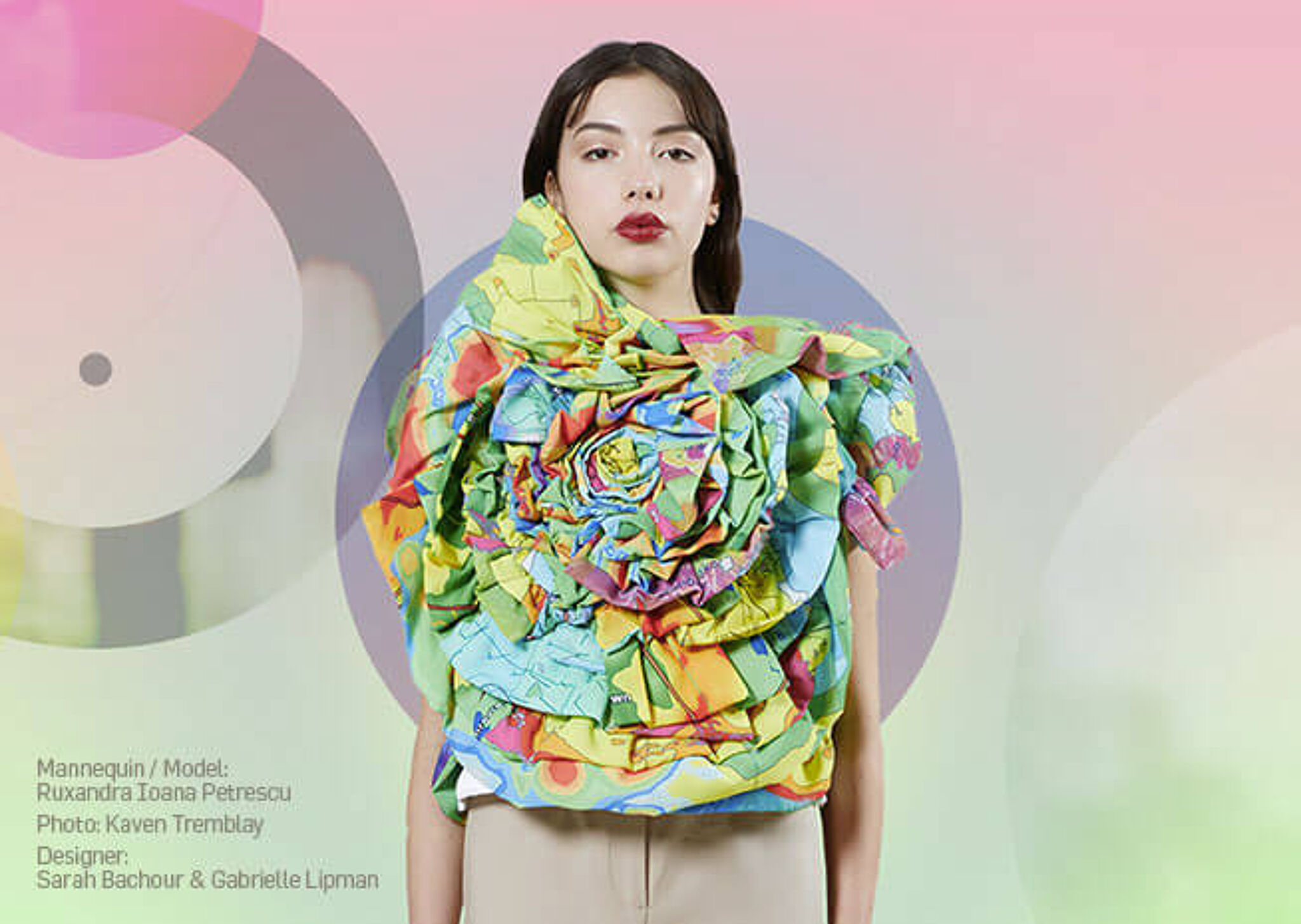A model with an oversized, colorful map-patterned ruffle scarf, against a soft, abstract background.