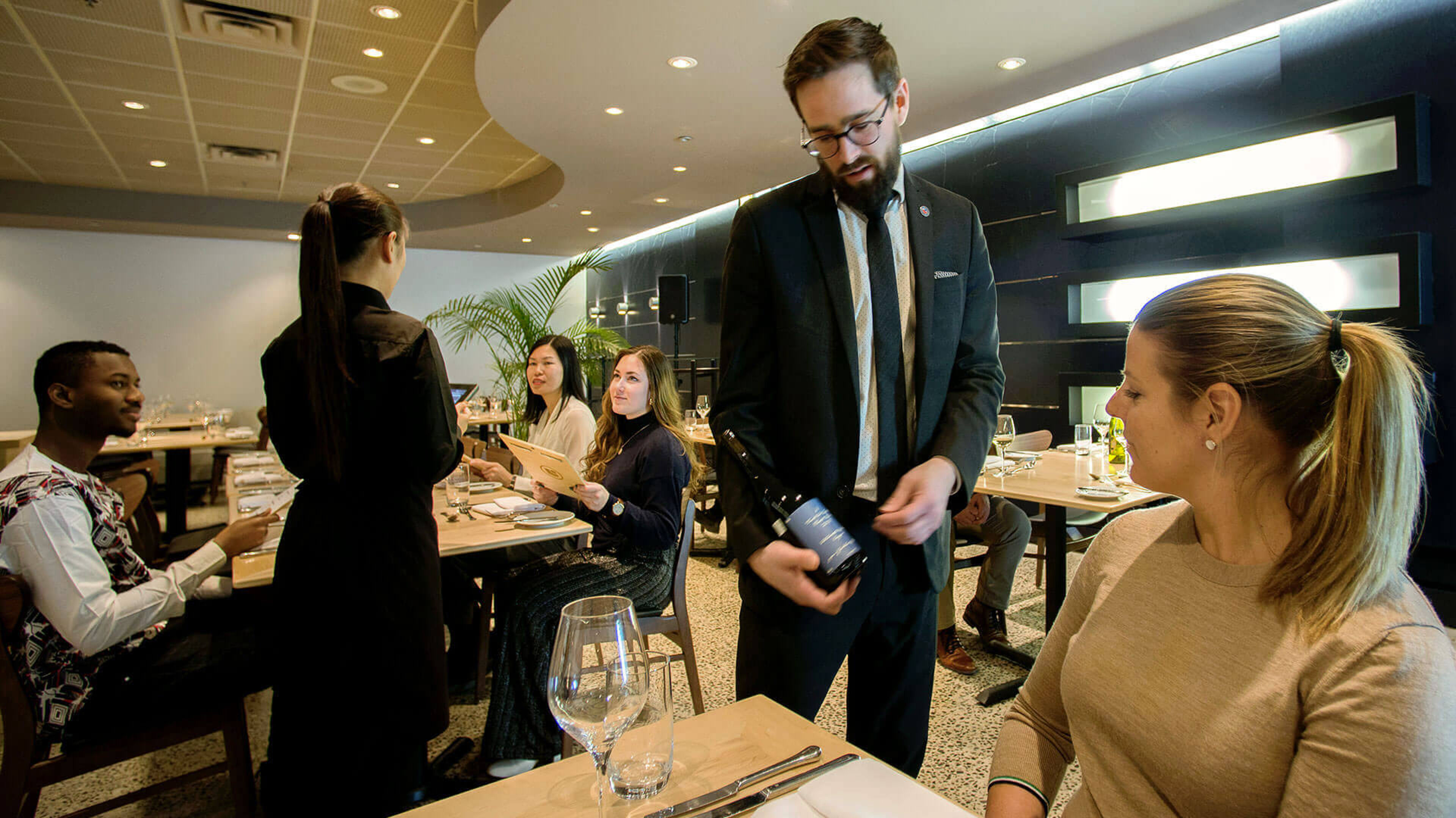 Patrons engage with attentive staff at a refined restaurant, enhancing the dining ambiance.