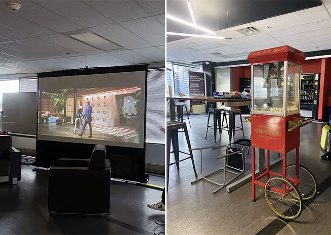 A spacious room featuring a large projector screen with a fashion presentation, and a vintage popcorn machine on the side
