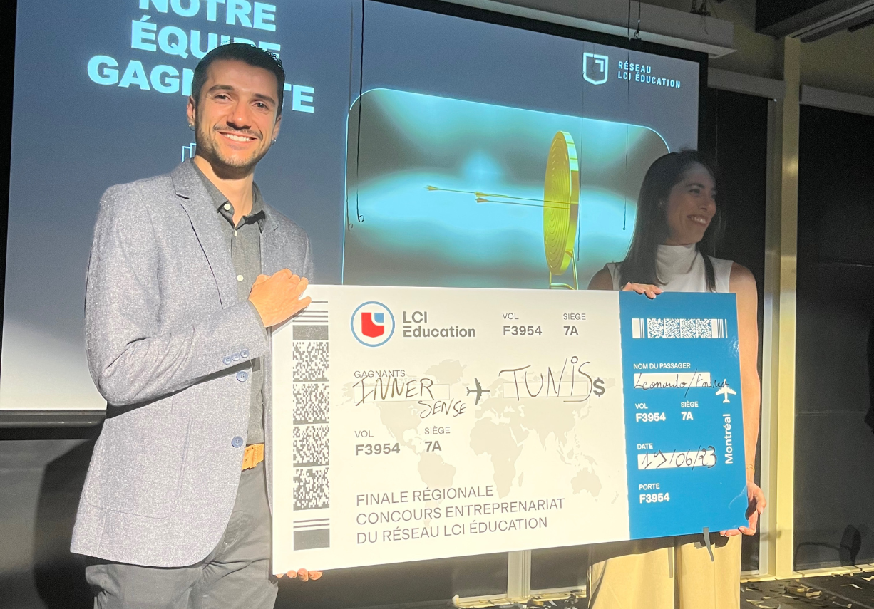 A man and woman proudly displaying a winning check from an entrepreneurship contest, with a celebratory background.