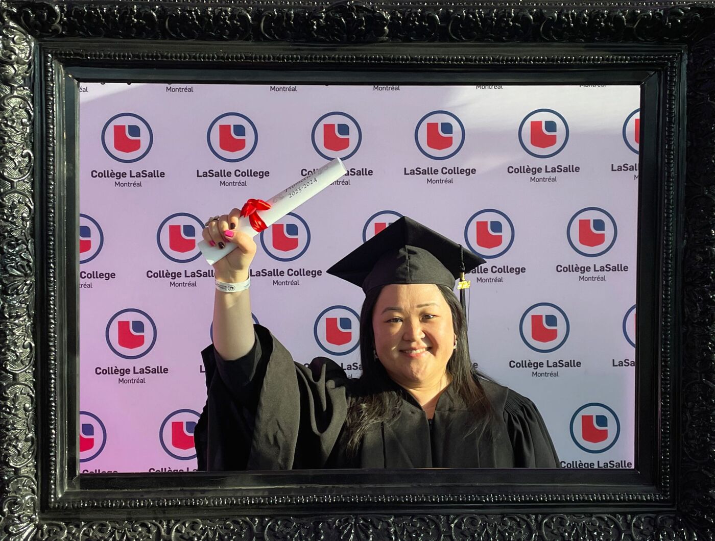 A woman in a graduation cap and gown holds her diploma in front of a backdrop featuring the Collège LaSalle logo.