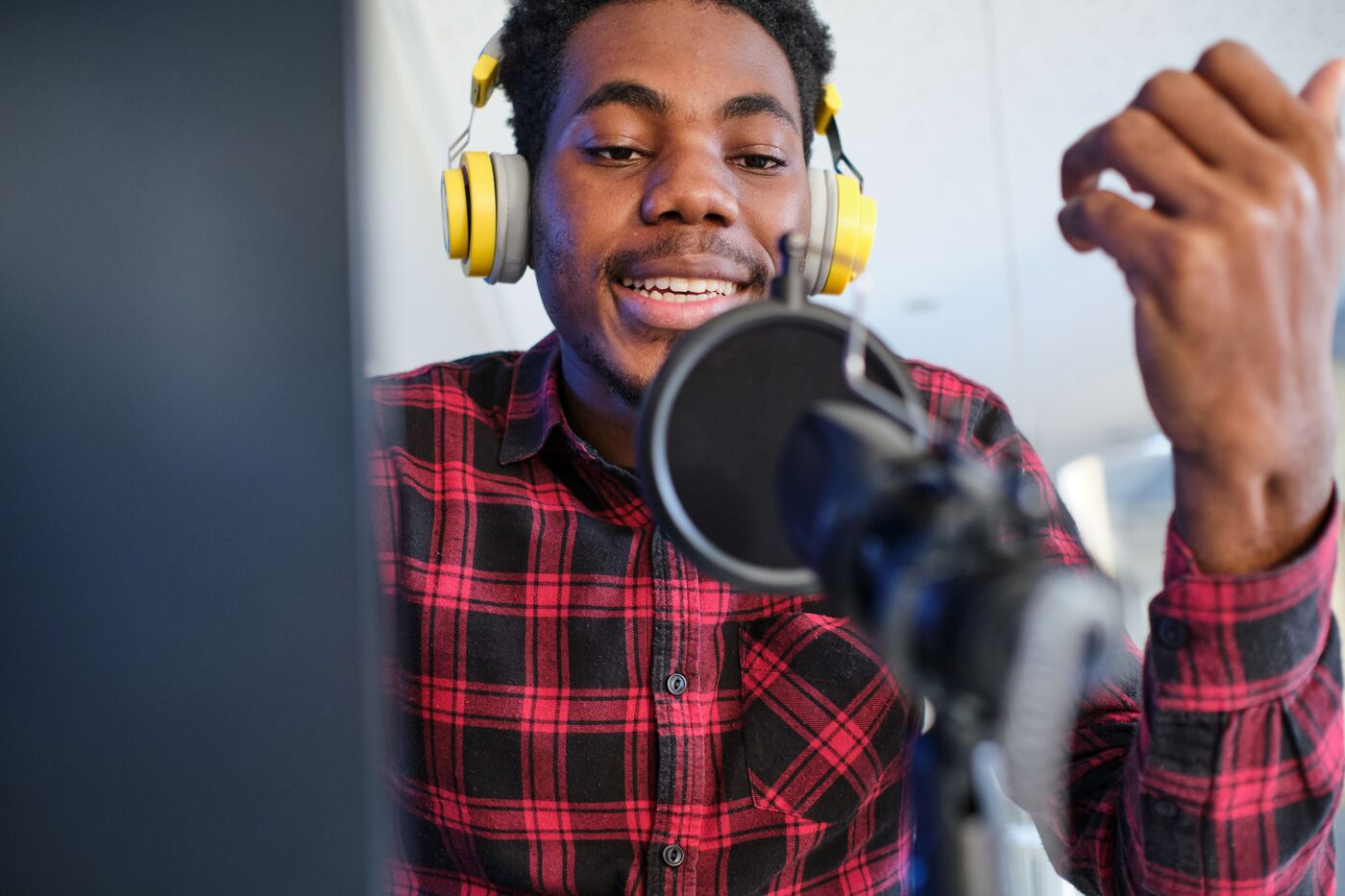 A man with headphones speaks into a microphone, likely recording a podcast or audio content.