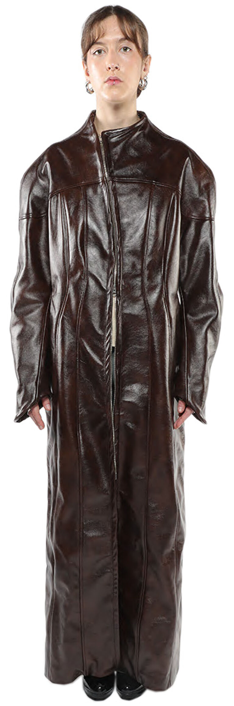 A full shot of a woman wearing a long, dark brown leather coat with a zipper closure.