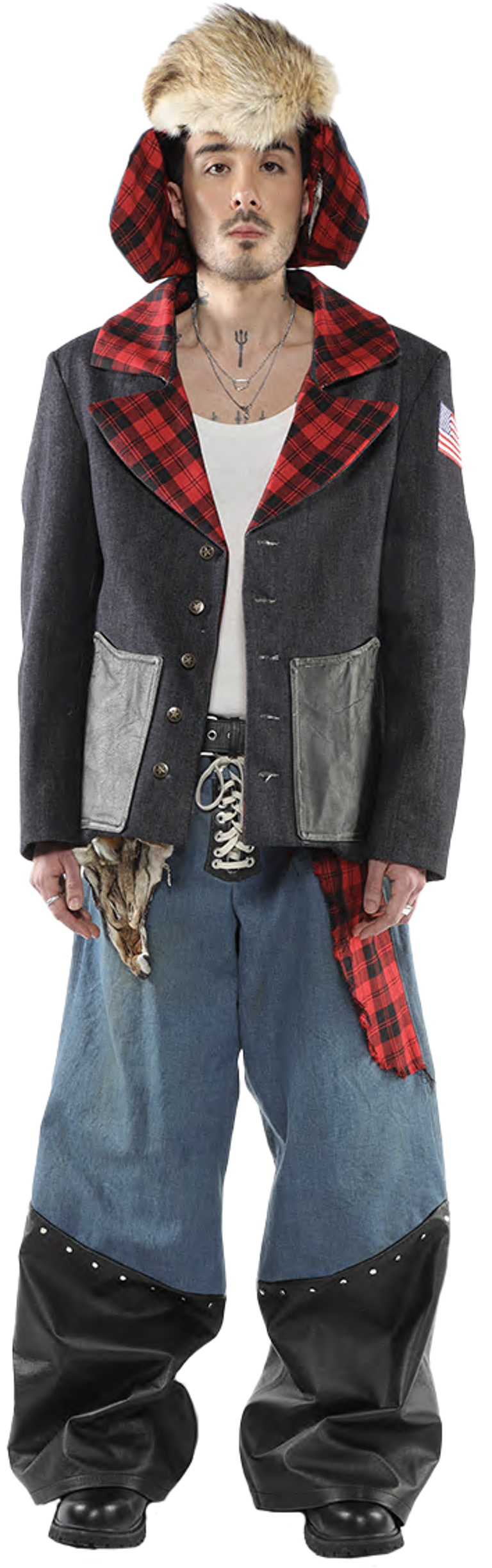 A person with a fur hat and a gray jacket with red and black plaid accents stands against a white background, wearing distressed denim pants with black leather accents.