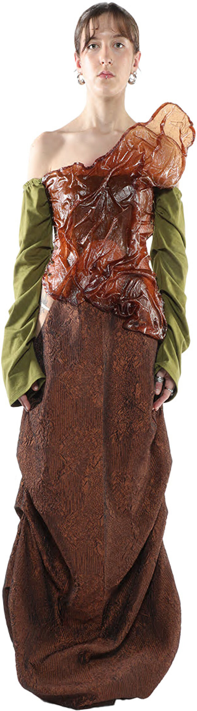 A woman with shoulder-length brown hair wears a brown, textured, asymmetrical dress with olive green sleeves and a sculpted, amber-colored bodice.